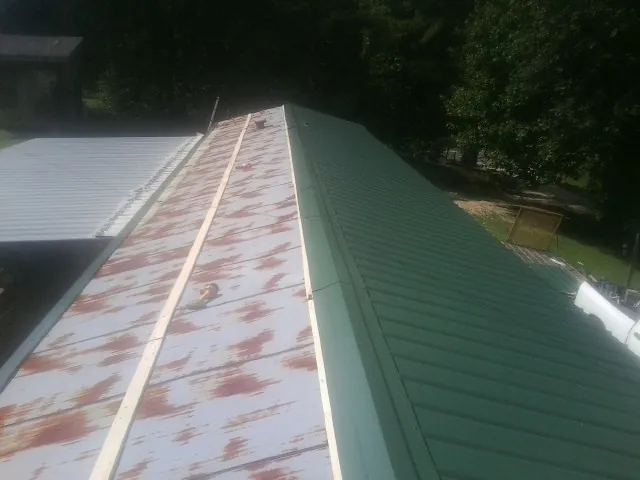 Old rusted panels beside newly installed green metal roofing — Wind Damage Roof Repair by Roofing Brothers in Chokoloskee