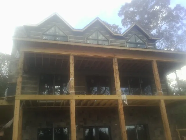 Dormers and porch framing on a large log home under construction — Roof Coating work by our crew in Chokoloskee