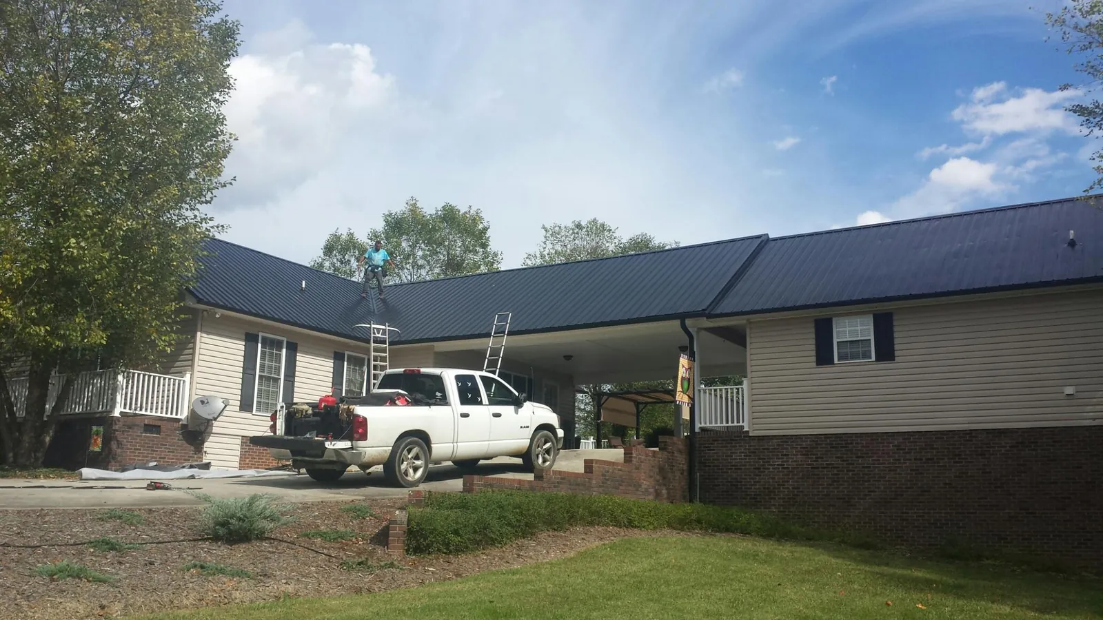 Black metal roof over a home and attached breezeway with ladders set in Chokoloskee