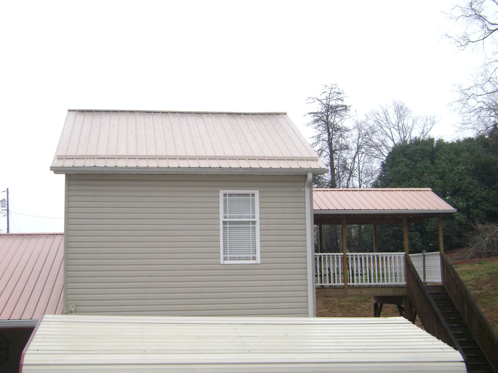 Tan metal roofs on a two story addition and attached porch, from a Roof Replacement job in Chokoloskee