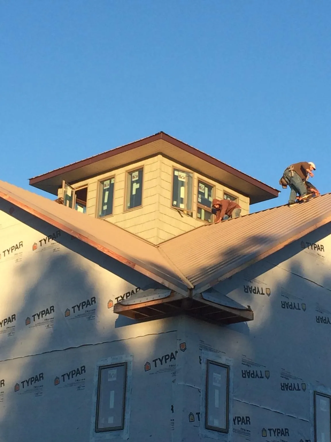 Roofers working around a rooftop cupola on a new metal roof at sunset — Roof Waterproofing in Chokoloskee by Roofing Brothers